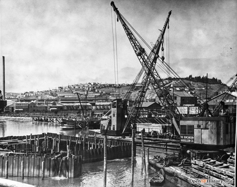 File:View Northwest from Islais Creek Bridge, 3rd Street. Duncanson-Harrelson Co. cranes, F. E. Booth Company (sardine cannery), Cargill warehouses. Potrero Hill with public housing in distance 1950s wnp37.03830.jpg